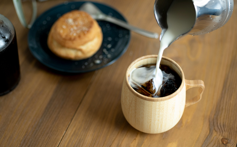 竹でできたカフェオレマグにミルクを注ぐ様子