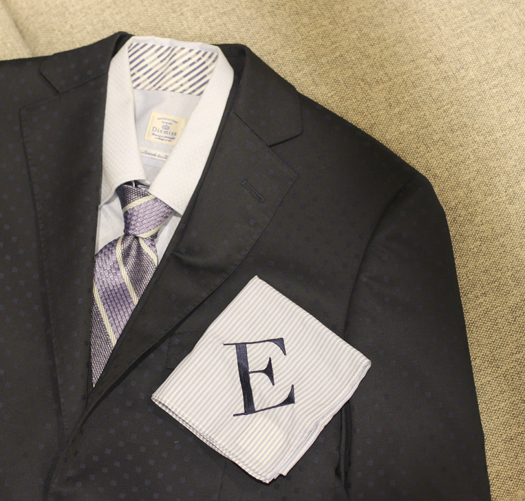 スーツの上に置かれたEのイニシャルハンカチ